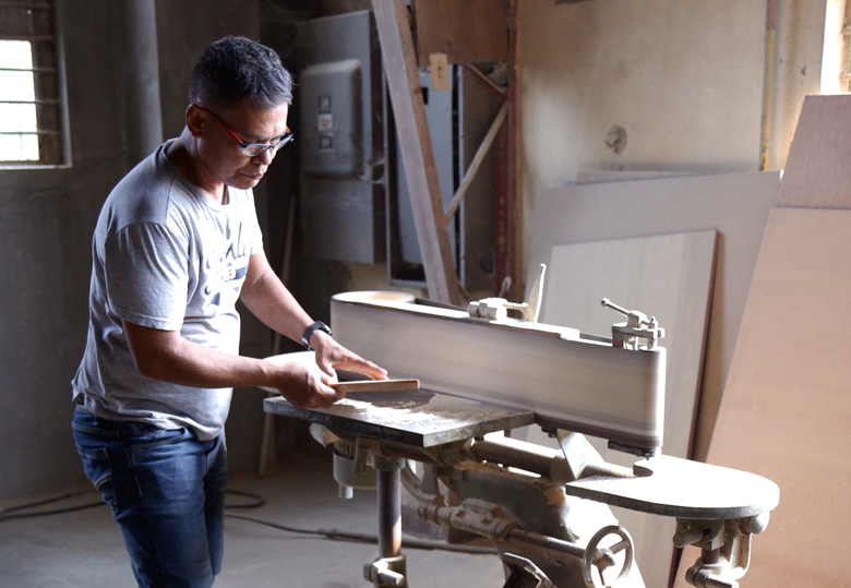 Balai Kamay carpenter in their workshop, examining a piece of wood for one of their products