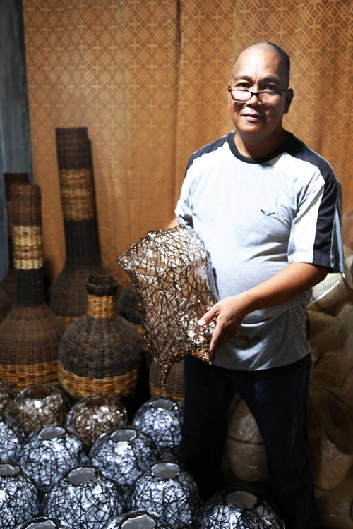 Renato Madrideo, owner of RLM Products, holding up a hand-crafted lamp