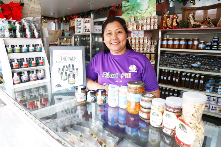 Myra Zandra Gestiada, owner of Vicky’s Pili and Food Products, leaning on a stall full of their bestsellers
