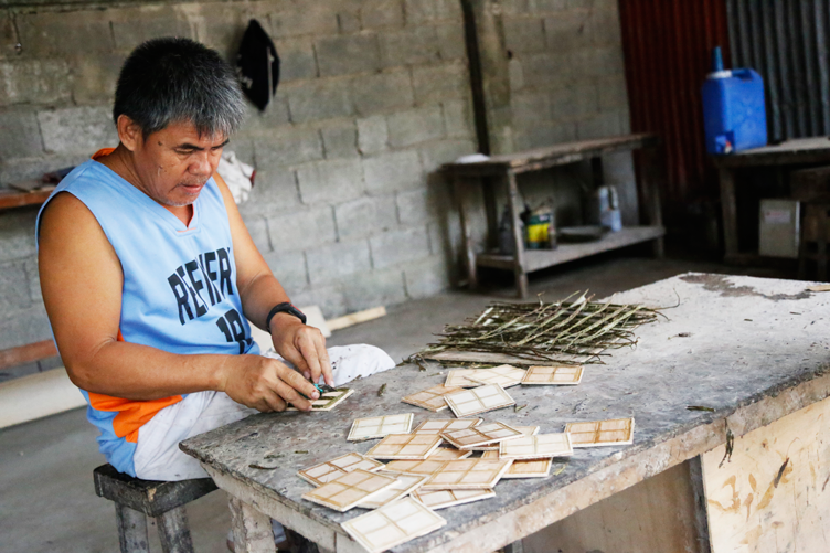 An employee of Babylan’s Cococrafts working painstakingly on the wooden parts of a box
