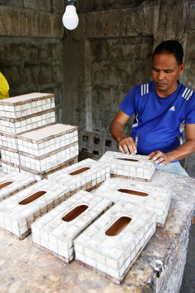 An employee of Babylan’s Cococrafts applying designs on the surface of a finished hand-crafted box