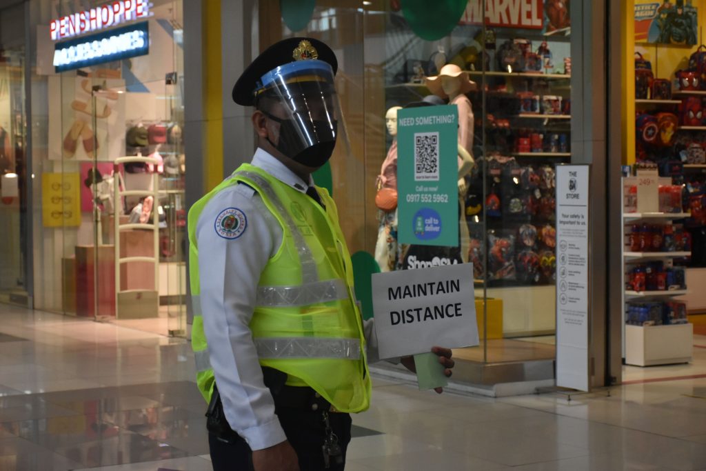 A guard showing a signage to maintain distance.