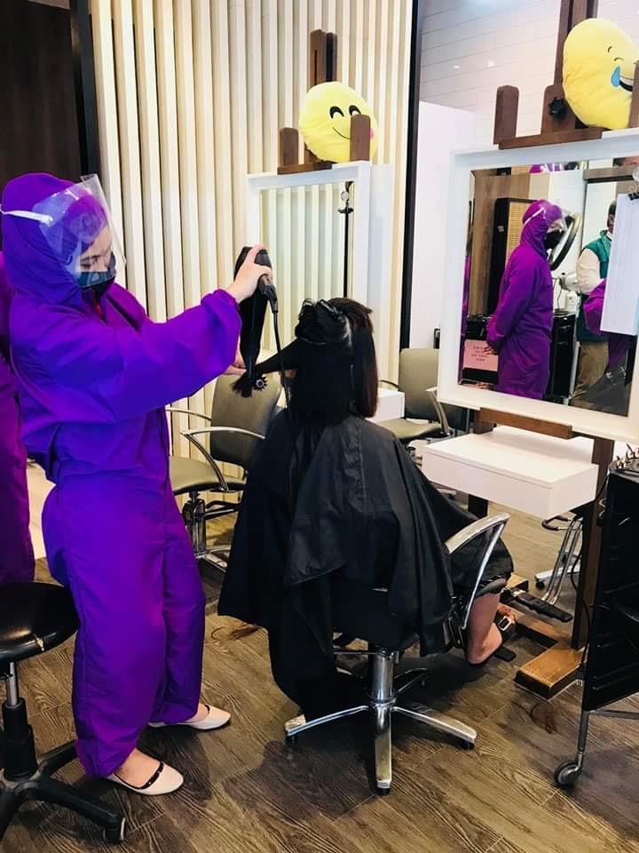 A salon worker, wearing a purple PPE, servicing a client in a salon in a mall in Region 9