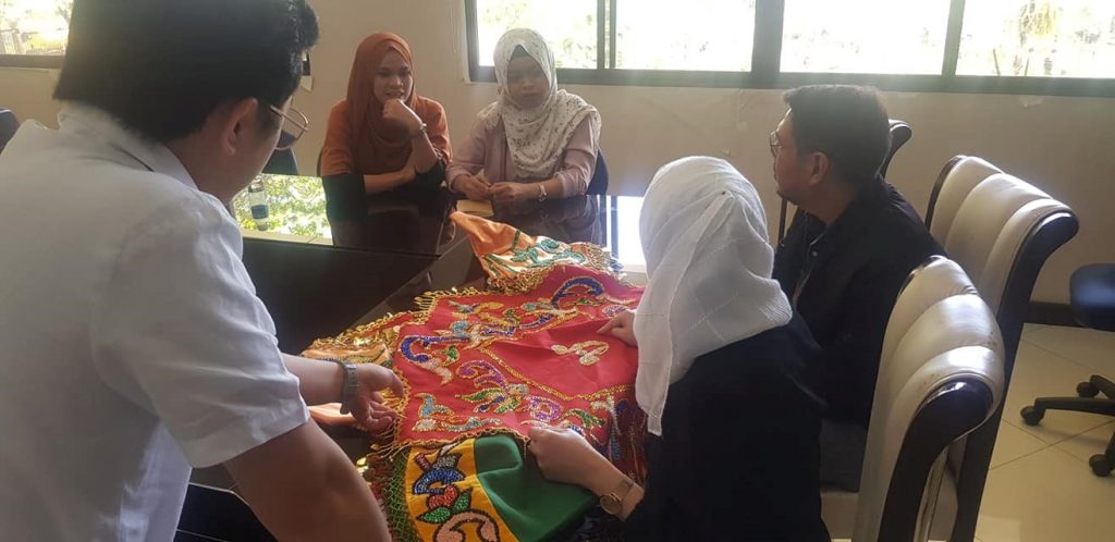Members of Raheemah Peace Weavers Producer Cooperative, MSU OKIR, and N’ditarun Tano discuss the production of Meranaw-inspired designs.