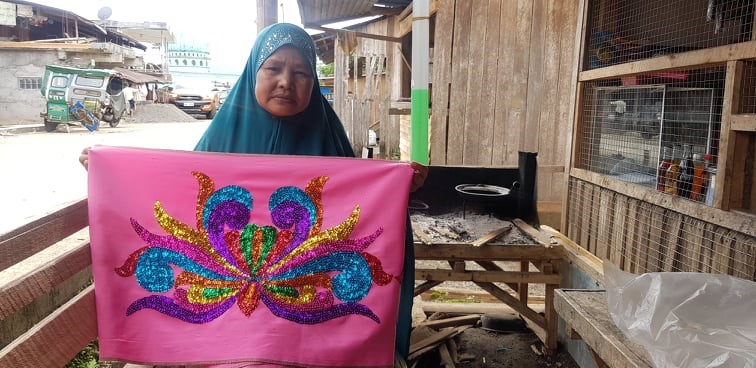 A member of Raheemah Peace Weavers Producer Cooperative shows the first completed mamandiang during the community quarantine, measuring 15 meters long.