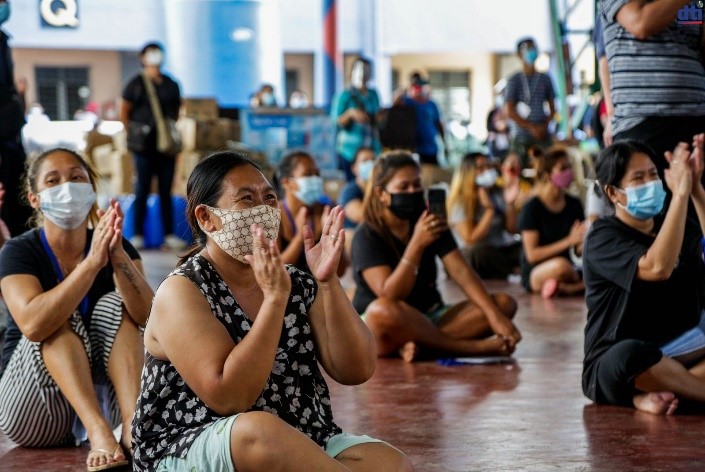 Mothers seated on the floor, clapping their hands during the short program