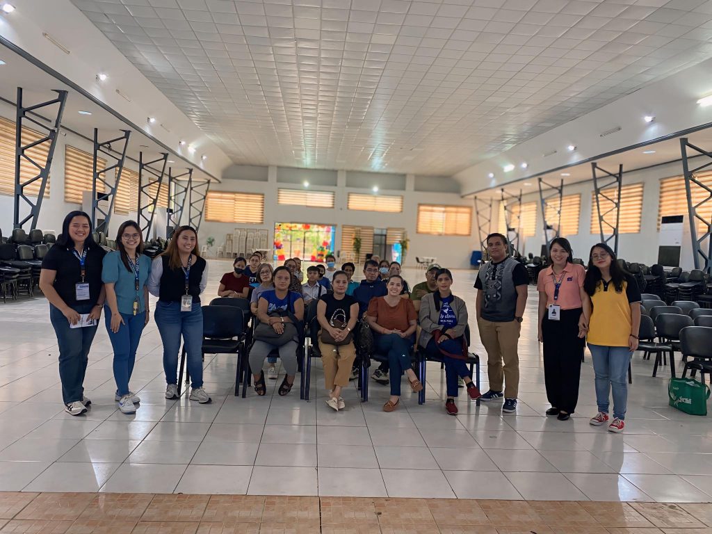 A group of people pose together in a spacious indoor area with chairs, featuring a colorful backdrop.