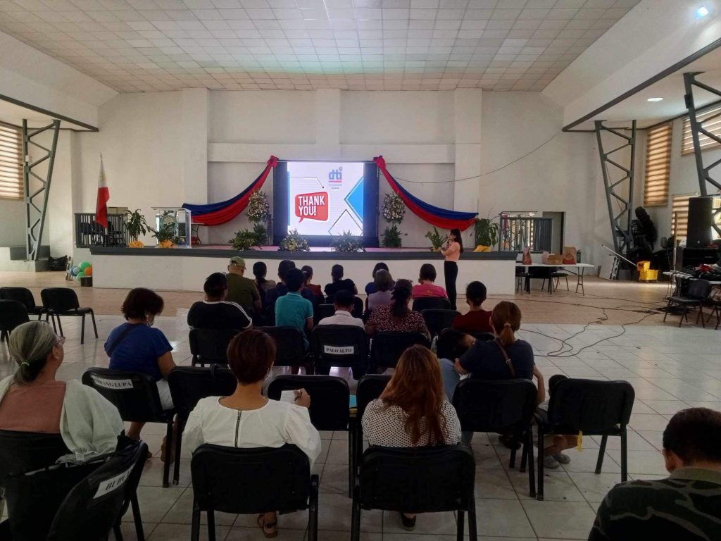 Audience in a hall watching a presentation on a screen that says "THANK YOU."