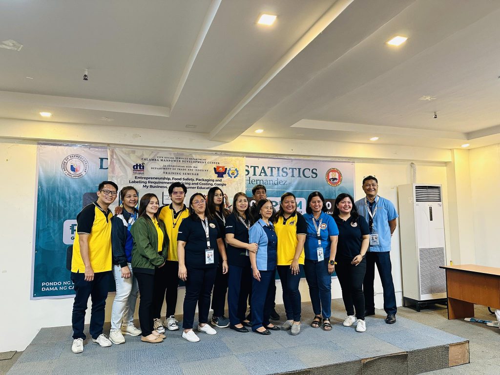 Group photo of professionals at a food safety seminar, standing in front of a presentation backdrop.