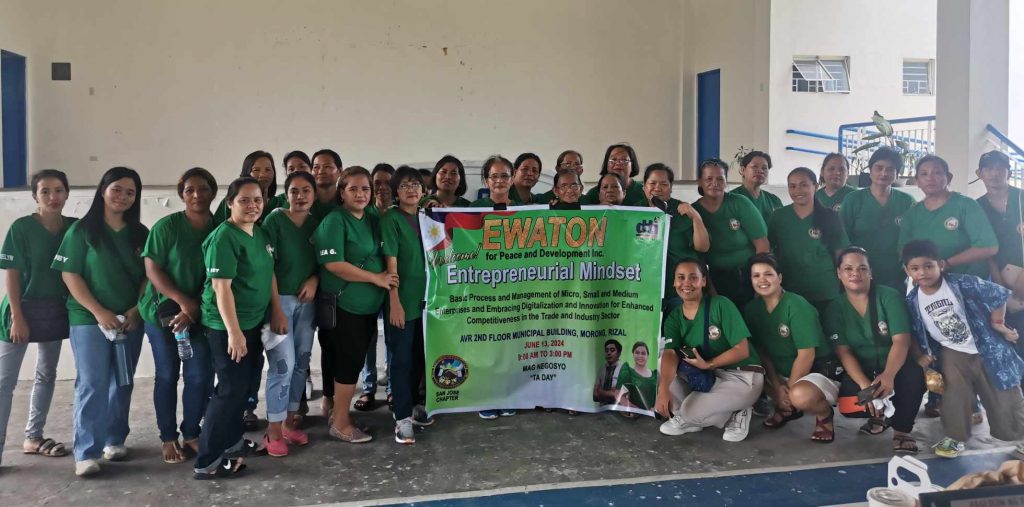 Group of women in green shirts holding a banner about an entrepreneurial mindset workshop.