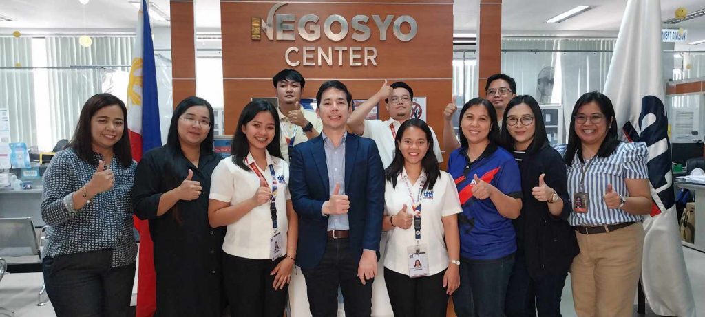 Group of people giving thumbs up in front of the Negosyo Center sign.