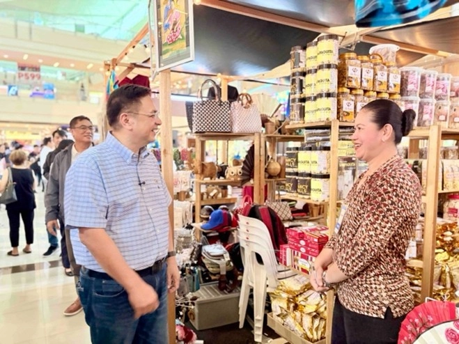 Muntinlupa City Mayor Ruffy Biazon smiles while talking to a local entrepreneur at Kultura Fest: Philippine Trade Fair. Behind them, a booth displays various locally made products, including bags, snacks, and handcrafted items, highlighting the creativity of Filipino MSMEs.