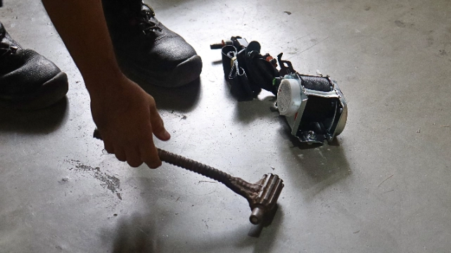 A person is seen holding a hammer, preparing to destroy a pile of safety belts on the ground. The safety belts are non-compliant with the corrosion test requirements under Philippine National Standards (PNS) 1892:2000 Amd. 01:2002. This destruction is supervised by the Department of Trade and Industry (DTI) to ensure that only compliant and quality safety belts are available in the market, protecting consumer welfare.