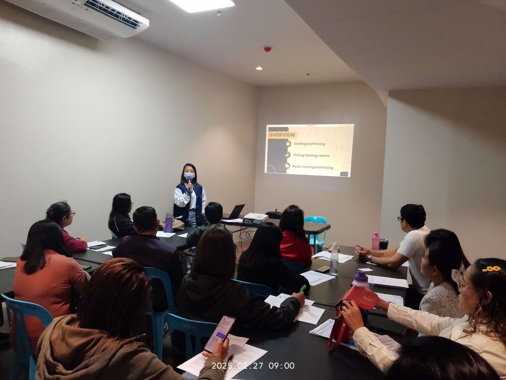 DTI-Laguna MSME seminar: Presenter giving a lecture on pricing and costing to group of seated attendees.