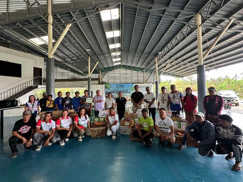 Group of coffee farmers and representatives from the Department of Trade and Industry (DTI) in Sultan Kudarat, Philippines, posing with newly distributed farm rejuvenation tools under the RAPID Growth Project.