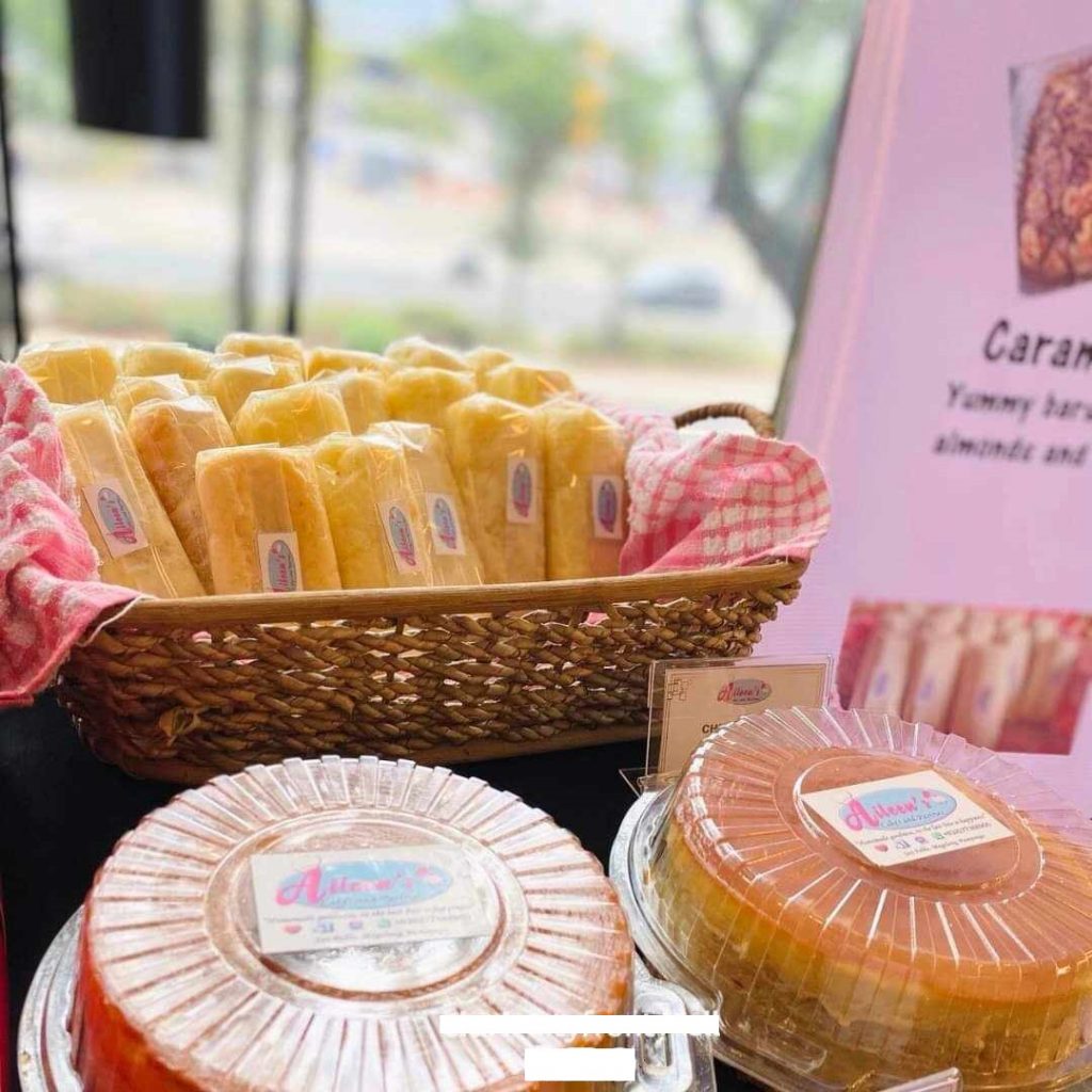 Cakes and wrapped pastries are displayed for sale, featuring "Aileen's Specialties" branding.