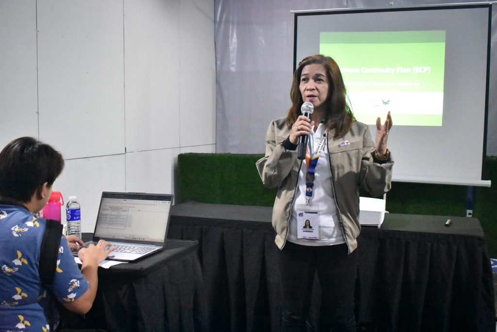 A woman is presenting, with a slide titled "Business Continuity Plan (BCP)" projected behind her.