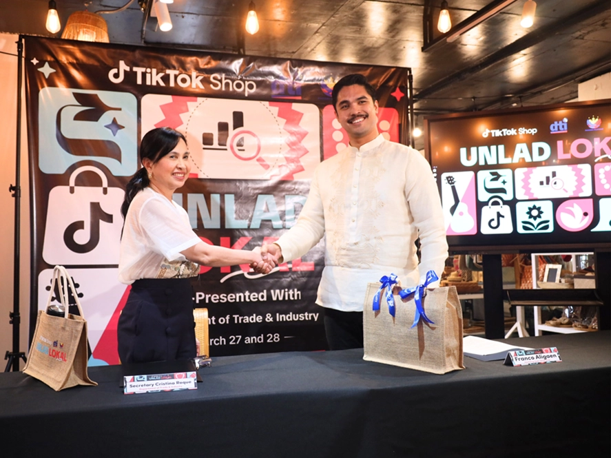 DTI Secretary Cristina A. Roque and TikTok Shop Marketing Lead Franco Aligaen shaking hands.