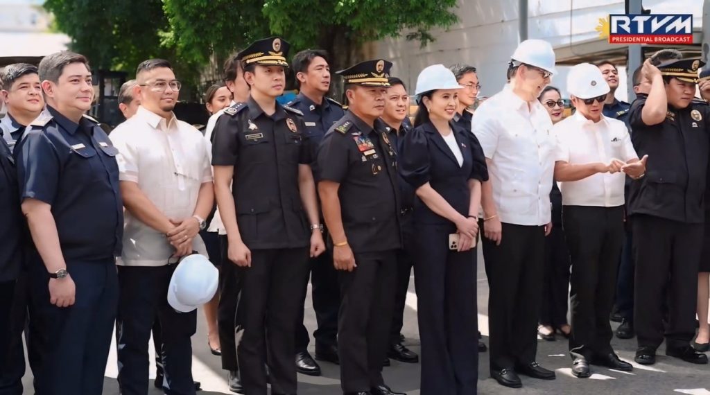 A group of Philippine government officials, some in uniform and others in formal attire with safety helmets, stand together outdoors at the Port of Manila. They appear to be overseeing the public condemnation of confiscated smuggled electronic cigarettes and vapor products, highlighting the government’s ongoing campaign against illicit trade and unregulated vape items.