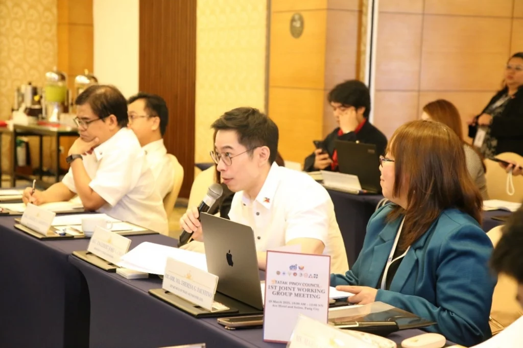 DTI Chief of Staff and Assistant Secretary Englebert Josef G. Chua speaks into a microphone while seated at a conference table during the inaugural joint meeting of the Tatak Pinoy Council Working Groups, discussing the Tatak Pinoy Strategy.