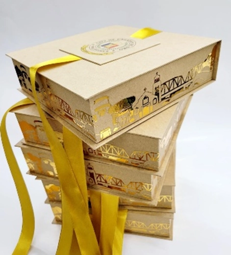 Stack of custom-designed cardboard takeout boxes by Purple Craft CDO, featuring gold foil illustrations and yellow ribbons, representing the business's adaptation during the pandemic.