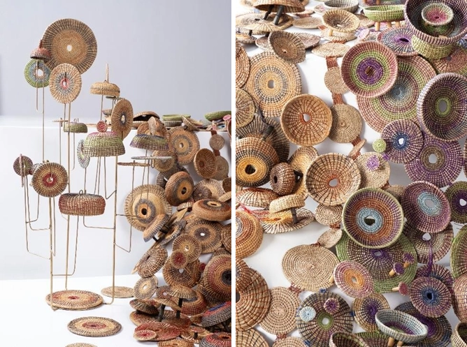 Sculptural artwork titled 'Hilaw, Layâ (Unripe, Withered)' by Leeroy New and Christina Gaston, featuring circular woven elements made of cogon grass, abaca, wax thread, and bamboo beads. The elements are arranged on thin vertical supports and scattered across a flat surface, symbolizing the cycle of life and the balance between growth and natural degradation.