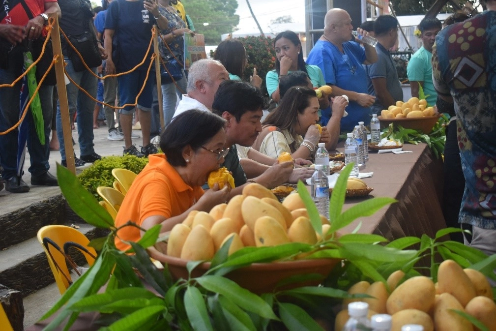 DTI Region 6 Director Rachel N. Nufable joins fellow government officials in the 'Mango Eat-All-You-Can' activity at the Guimaras Provincial Capitol Grounds during the Manggahan Festival 2025 on May 16, 2025.