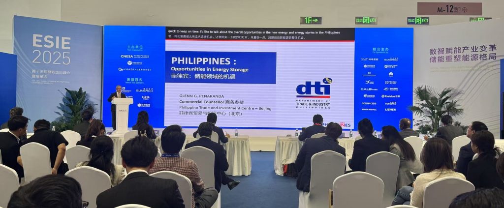 A medium shot of a conference hall shows Glenn G. Peñaranda, who appears to be of East Asian descent, at a podium. The background displays a screen with the text "PHILIPPINES: Opportunities in Energy Storage" in both English and Chinese. The setting suggests a presentation or lecture at an international conference.