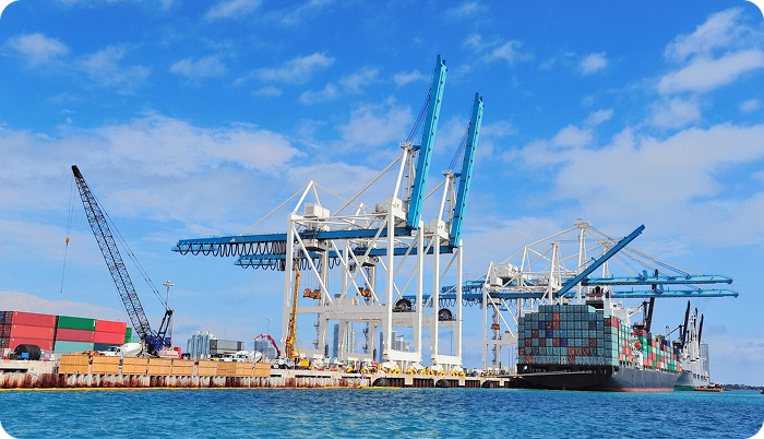 Docked container ship at port with cranes in background Docked container ship at port with cranes in background