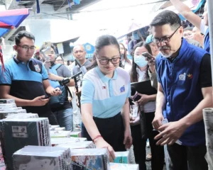 DTI Secretary Cristina A. Roque and Assistant Secretary Agaton Teodoro Uvero inspecting school supplies during a price monitoring activity at Baclaran market, accompanied by other officials and staff.