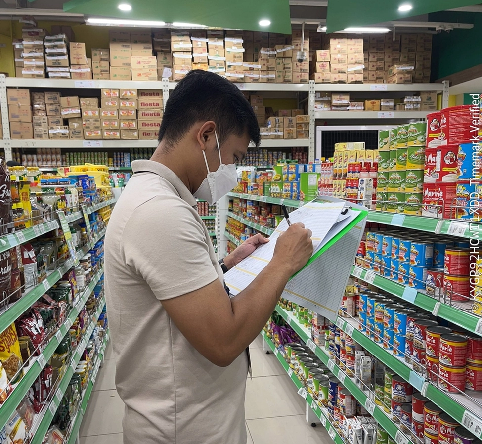 DTI personnel conducting price and supply monitoring in a grocery store aisle in Eastern Visayas, following the state of calamity declaration. The individual is wearing a white polo shirt and face mask, holding a clipboard while inspecting shelves stocked with canned goods and other essentials. DTI personnel conducting price and supply monitoring in a grocery store aisle in Eastern Visayas, following the state of calamity declaration. The individual is wearing a white polo shirt and face mask, holding a clipboard while inspecting shelves stocked with canned goods and other essentials.