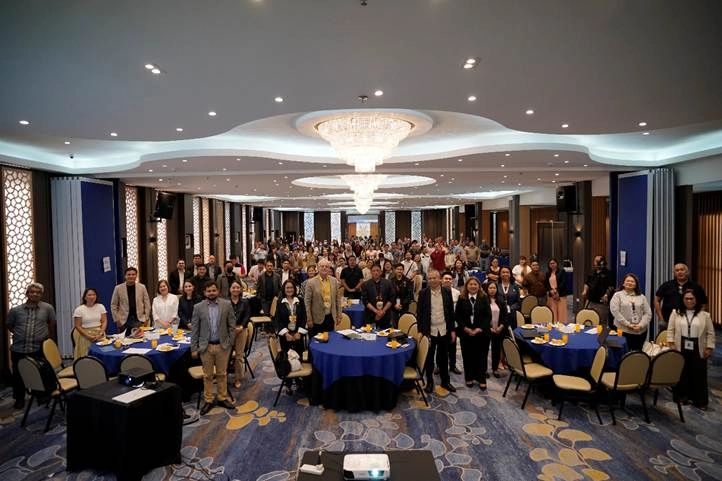 Participants attend the 'Mainstreaming Energy Efficiency in MSMEs' Investment Roadshow in a spacious conference hall in Cagayan de Oro, seated at round tables with blue tablecloths, as part of DTI’s initiative to promote sustainable business practices in Mindanao.