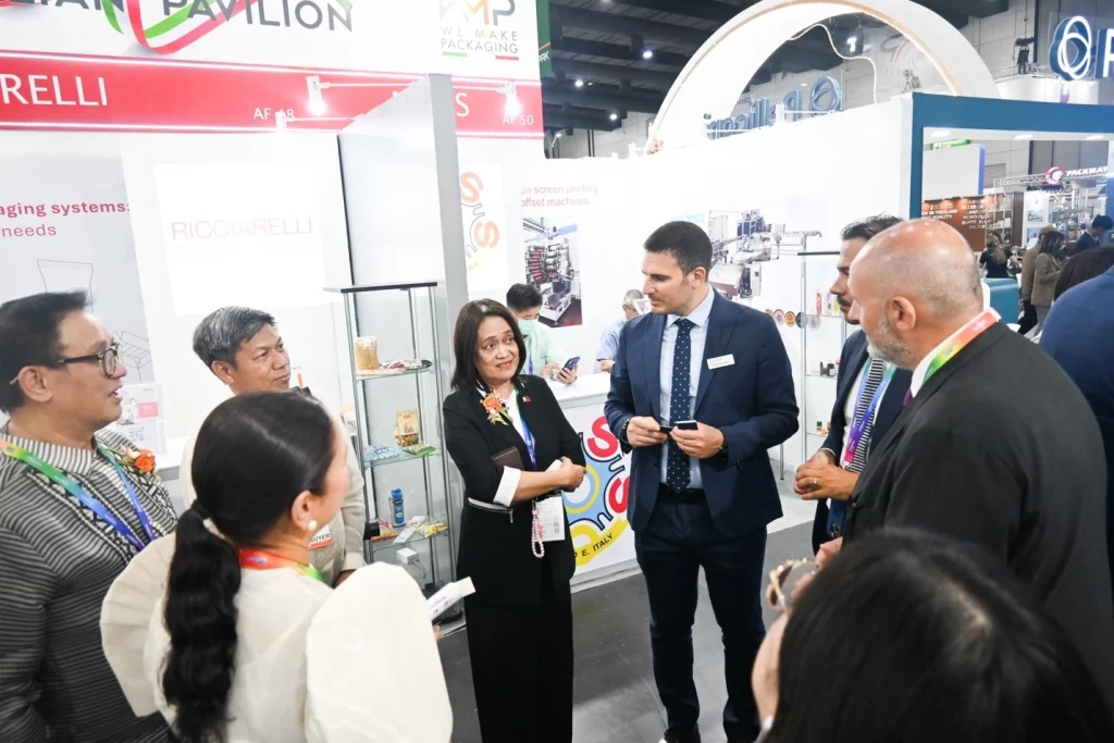 Usec. Blesila Lantayona and Asec. Dominic Tolentino at the Ricciarelli booth during ProPak Asia 2025, engaging in discussion with other delegates amid displays of packaging systems and promotional materials.