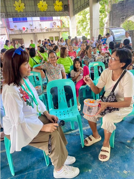DTI Assistant Secretary Leonila Baluyut interacts with butterfly breeders and community members during the Bila-Bila Festival 2025 in Boac, Marinduque, with a decorated stage and attendees in the background.