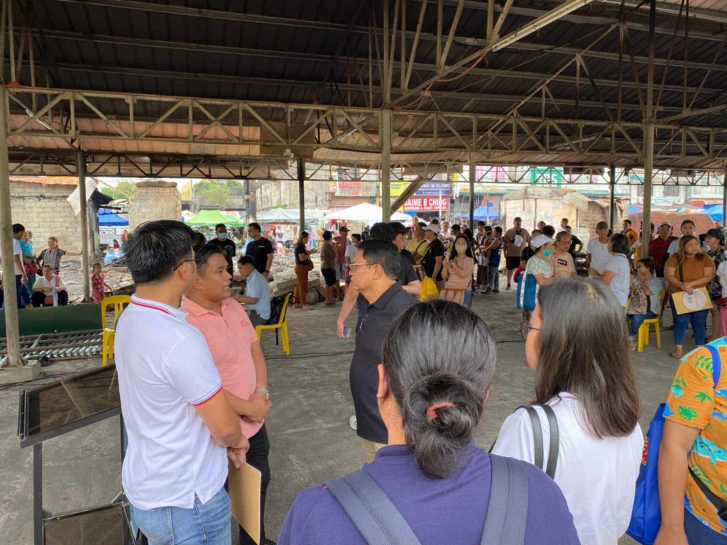Government officials from Senator Bong Go’s office and DTI-Laguna provide relief assistance and introduce livelihood recovery programs to fire victims at Santa Cruz public market, highlighting the Pangkabuhayan sa Pagbangon at Ginhawa initiative and collaborative disaster response efforts.