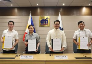 DTI Secretary Ma. Cristina A. Roque, Asec. Englebert, Asec. Ablan, and Alex Lagata, Jr. pose with signed documents during the MOU signing ceremony with Japan’s Rinna Co. Ltd. for Project TRINA, with the DTI Philippines logo and national flags in the background.
